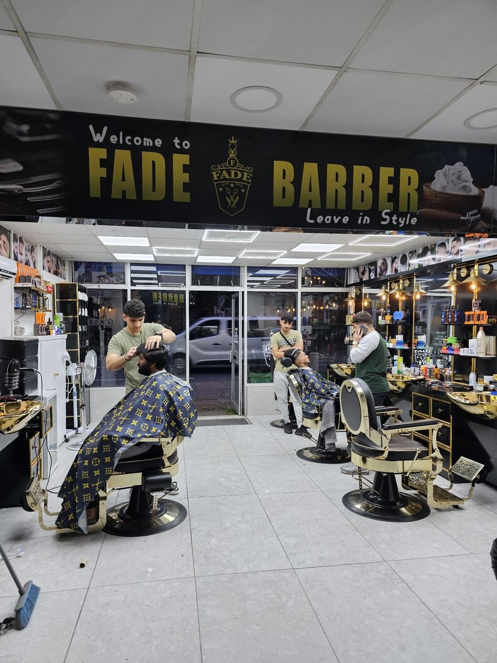 Inside Fade Barber: the Welcome to Fade Barber sign above black and gold stations